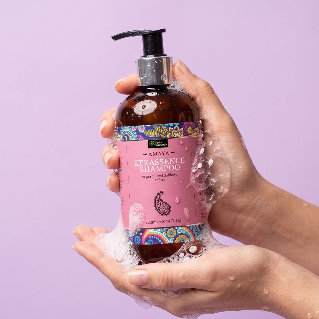 Shampoo bottle with black pump, held in hands with visible foam
