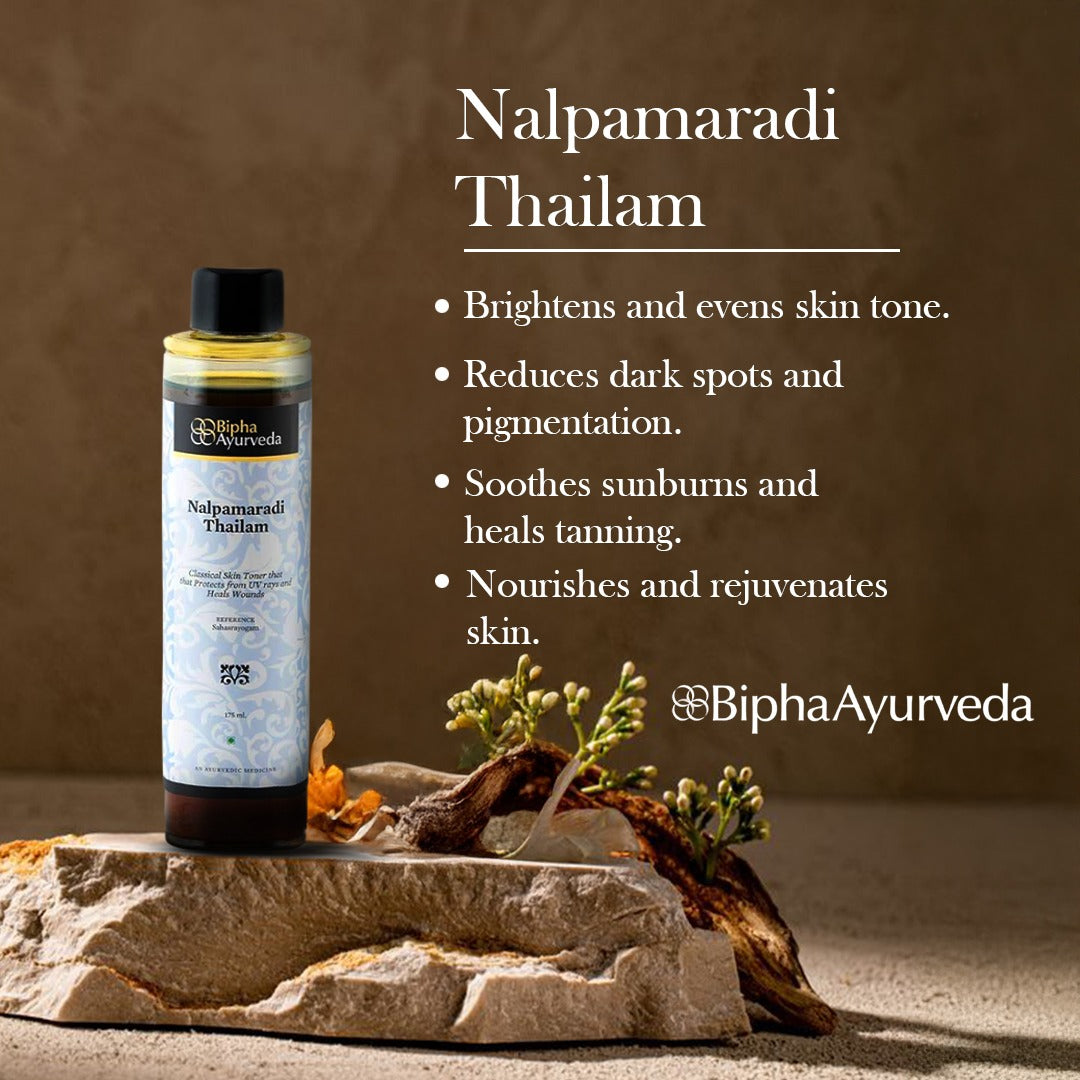 Ayurveda skin oil bottle with gold pump, with herbs beside it on stone surface.