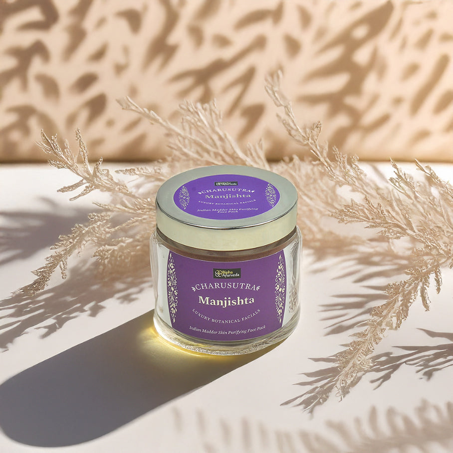 Face pack jar with purple label on cream container, surrounded by dry plant leaves